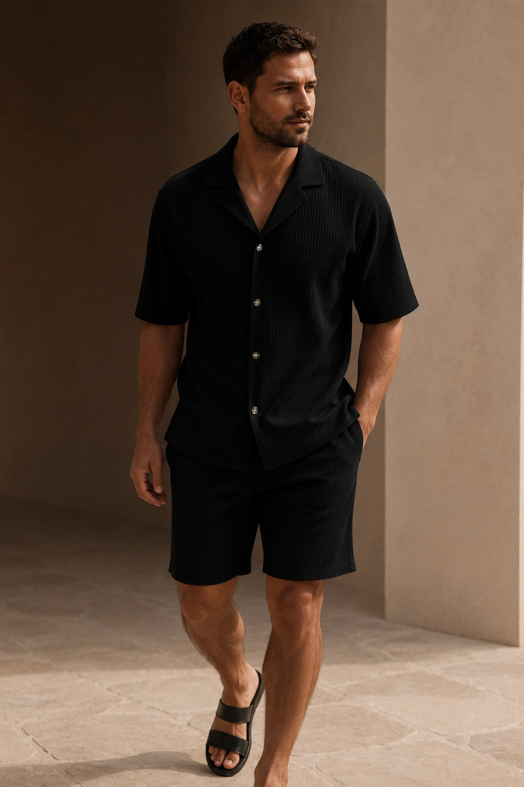 Uomo che indossa il Portofino Summer Set™ Nero con naturale eleganza e una mano in tasca. Lo scatto valorizza il colore nero sofisticato, le linee pulite del design italiano e il comfort premium del completo estivo.