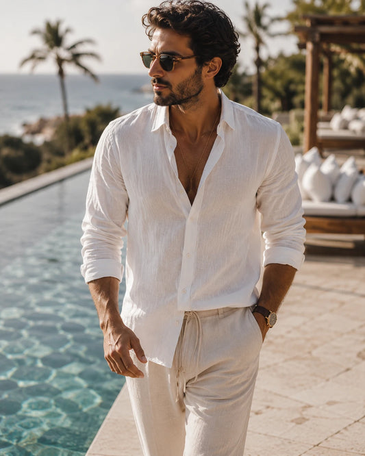 Modello che indossa la Riviera Linen Shirt™ Bianco in un elegante contesto mediterraneo. L'immagine mette in risalto il tessuto leggero, la vestibilità rilassata e il design italiano raffinato, ideale per le giornate estive.